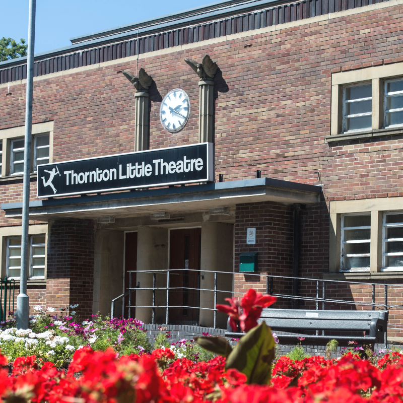 Thornton Little Theatre exterior with red flowers in foreground